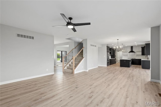 1 Hadleigh, Windsor Park, Lake St Louis, MO 63367 - unfurnished living room featuring a chandelier, a sink, light wood-style flooring, stairs, and ceiling fan