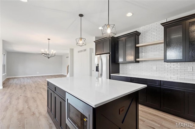 1 Hadleigh, Windsor Park, Lake St Louis, MO 63367 - kitchen with appliances with stainless steel finishes, open shelves, decorative backsplash, light countertops, and light wood-style floors