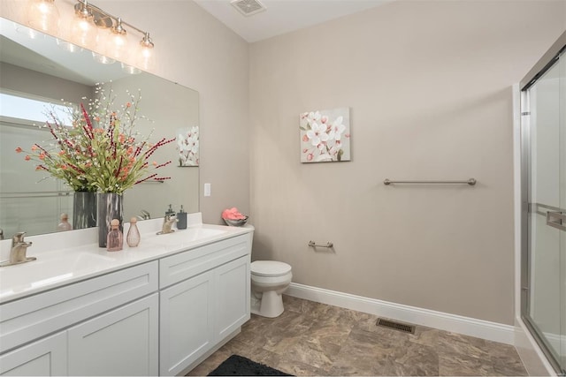 bathroom with double vanity, toilet, baseboards, and a shower with shower door