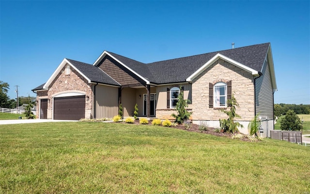 view of front facade featuring an attached garage, a front yard, stone siding, and driveway