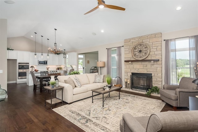 living area with healthy amount of natural light, dark wood-style floors, a ceiling fan, a fireplace, and high vaulted ceiling