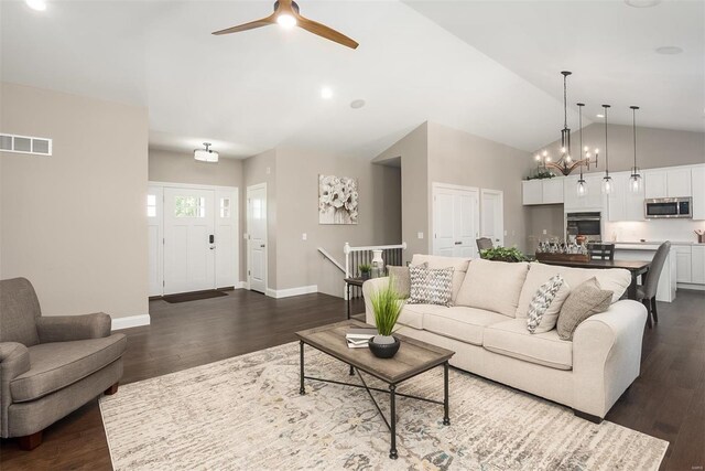 living room with ceiling fan, dark wood finished floors, high vaulted ceiling, baseboards, and a chandelier
