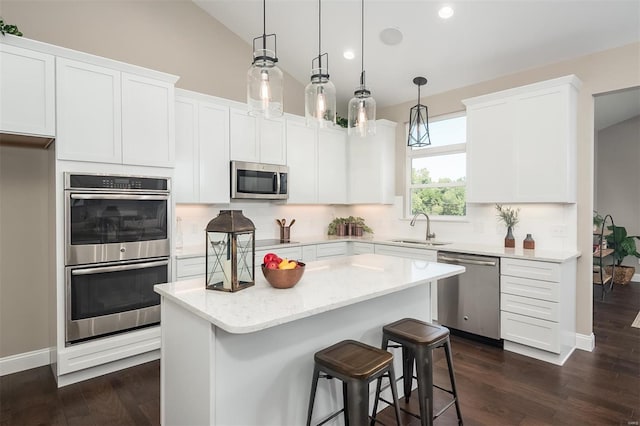 kitchen featuring stainless steel appliances, a sink, dark wood-style floors, a center island, and lofted ceiling