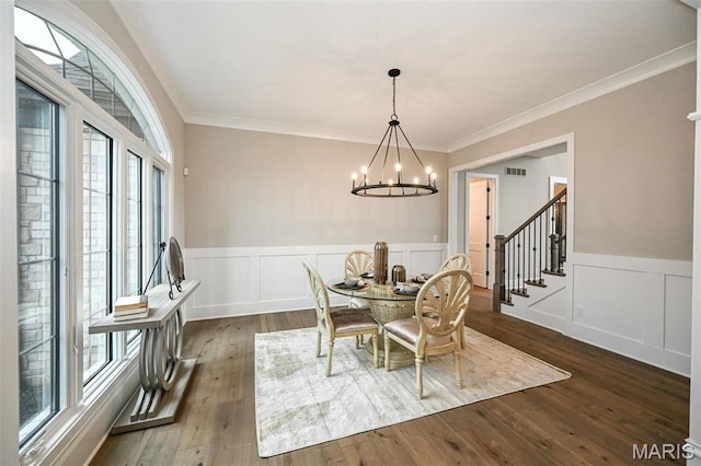 712 Silver Buck Ln, Chesterfield, MO 63005 - dining area featuring a chandelier, a wainscoted wall, dark wood-style floors, crown molding, and a decorative wall