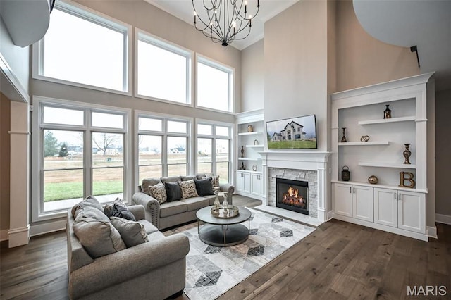 712 Silver Buck Ln, Chesterfield, MO 63005 - living area with a high ceiling, a stone fireplace, dark wood-type flooring, a chandelier, and healthy amount of natural light