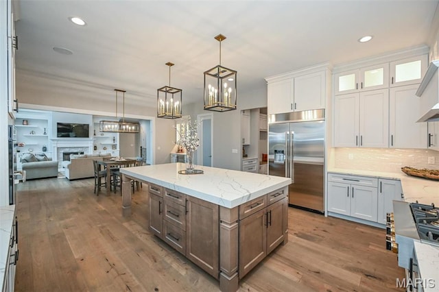 712 Silver Buck Ln, Chesterfield, MO 63005 - kitchen with appliances with stainless steel finishes, wood finished floors, white cabinetry, light stone countertops, and decorative backsplash