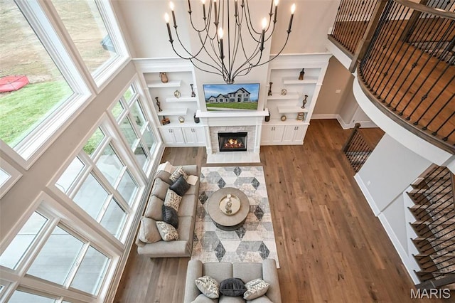 712 Silver Buck Ln, Chesterfield, MO 63005 - living room featuring a high ceiling, dark wood-style flooring, a chandelier, a stone fireplace, and built in shelves