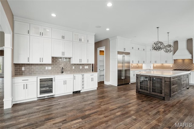 724 Silver Buck Ln, Chesterfield, MO 63005 - kitchen with stainless steel appliances, beverage cooler, custom range hood, light countertops, and white cabinetry