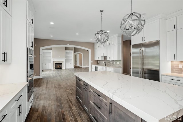 724 Silver Buck Ln, Chesterfield, MO 63005 - kitchen with high end refrigerator, a lit fireplace, open floor plan, white cabinets, and recessed lighting
