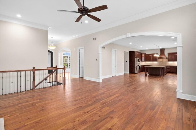 744 Silver Buck Ln, Chesterfield, MO 63005 - unfurnished living room featuring a ceiling fan, wood finished floors, arched walkways, recessed lighting, and crown molding