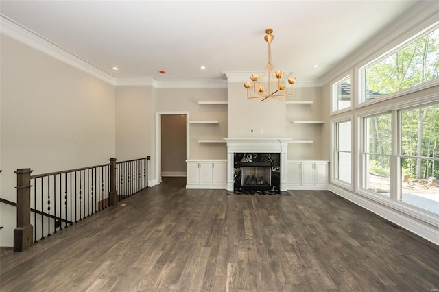 unfurnished living room with dark wood finished floors, a chandelier, ornamental molding, a high end fireplace, and built in features