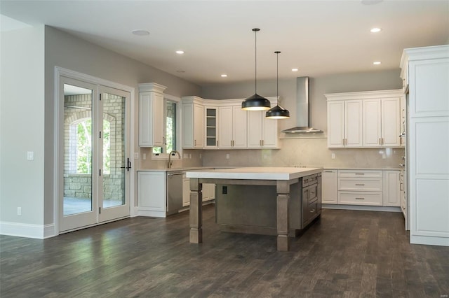 kitchen featuring wall chimney exhaust hood, dishwasher, dark wood finished floors, light countertops, and white cabinets