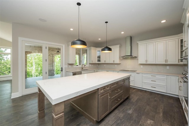 kitchen featuring wall chimney range hood, white cabinets, glass insert cabinets, recessed lighting, and a kitchen island