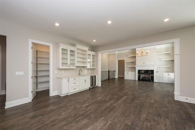 unfurnished living room with wine cooler, dark wood-style floors, baseboards, wet bar, and recessed lighting