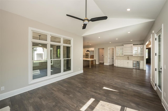 unfurnished living room with ceiling fan, vaulted ceiling, beverage cooler, dark wood finished floors, and recessed lighting