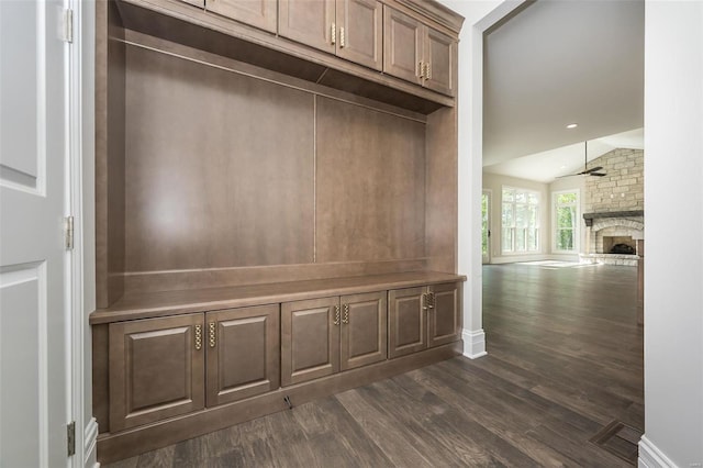 mudroom with lofted ceiling, dark wood-style flooring, a large fireplace, ceiling fan, and baseboards