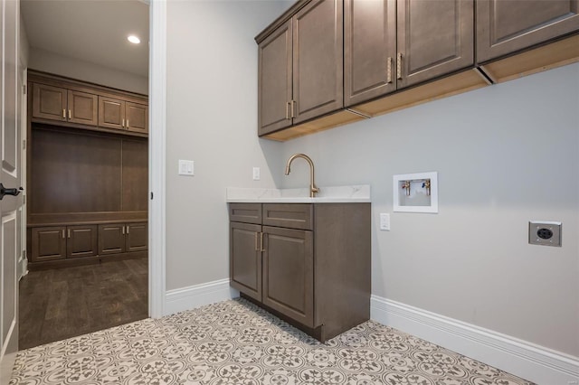 laundry room featuring electric dryer hookup, baseboards, hookup for a washing machine, cabinet space, and tile patterned flooring