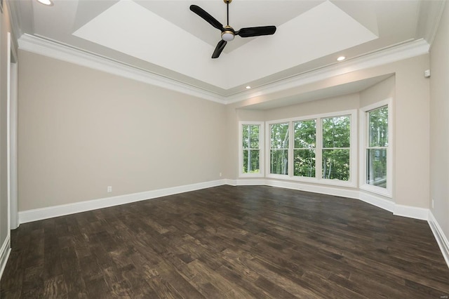 empty room with crown molding, a raised ceiling, baseboards, dark wood finished floors, and ceiling fan
