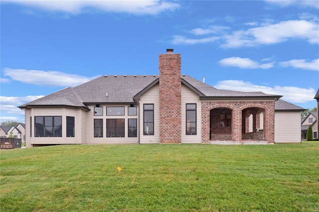 back of house with a shingled roof, a chimney, and a yard