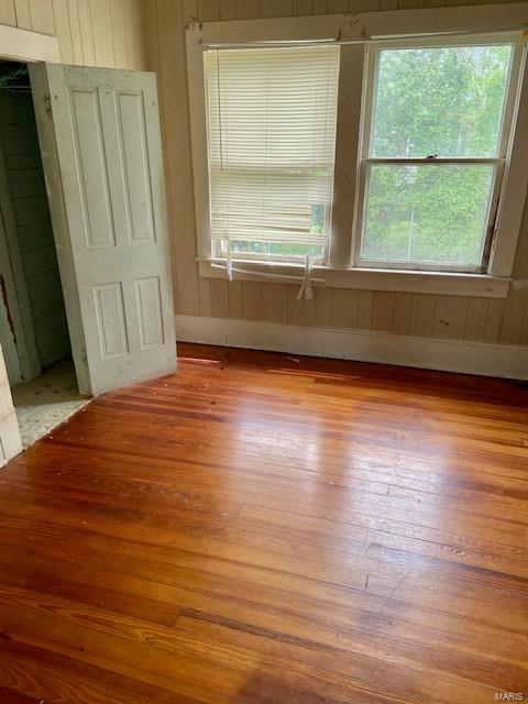 332 S Elm, Dexter, MO 63841 - unfurnished room with light wood-style flooring and wood walls