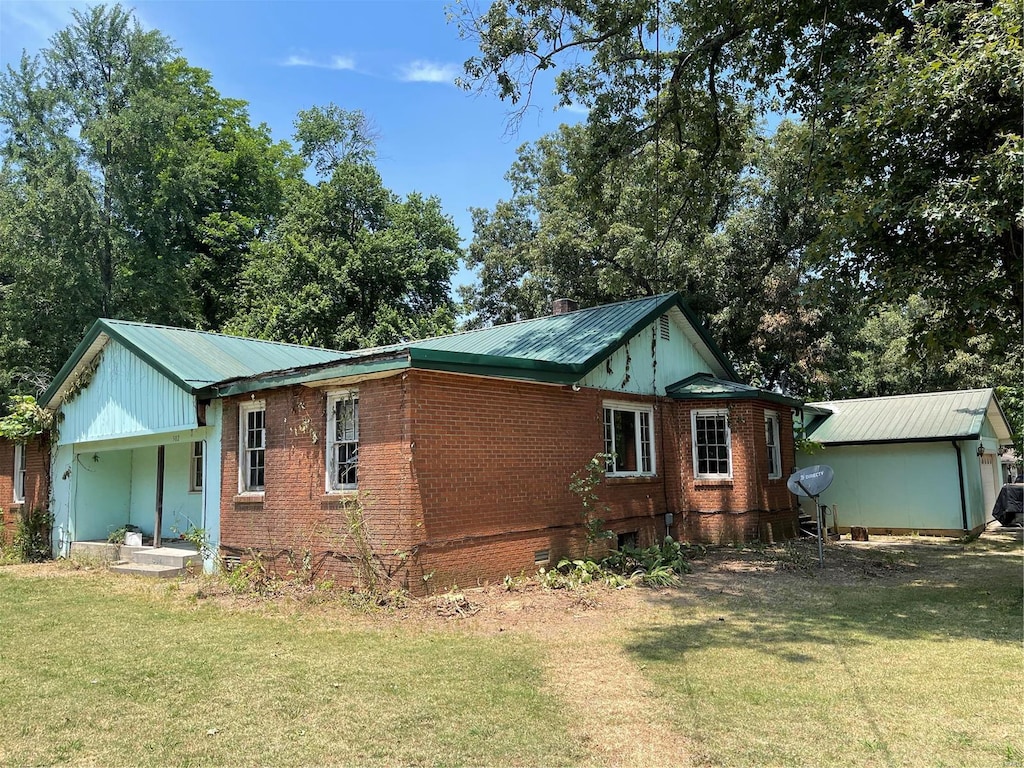 502 Chautauqua, Dexter, MO 63841 - view of side of property with brick siding, a lawn, and metal roof