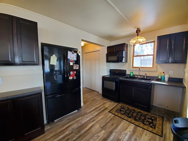 801 S Front St, La Grange, MO 63448 - kitchen featuring black appliances, wood finished floors, a sink, a chandelier, and dark countertops