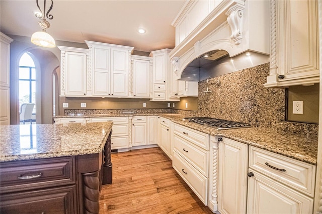 6708 Brown Ln, Poplar Bluff, MO 63901 - kitchen with stainless steel gas stovetop, arched walkways, light wood-style flooring, decorative backsplash, and premium range hood