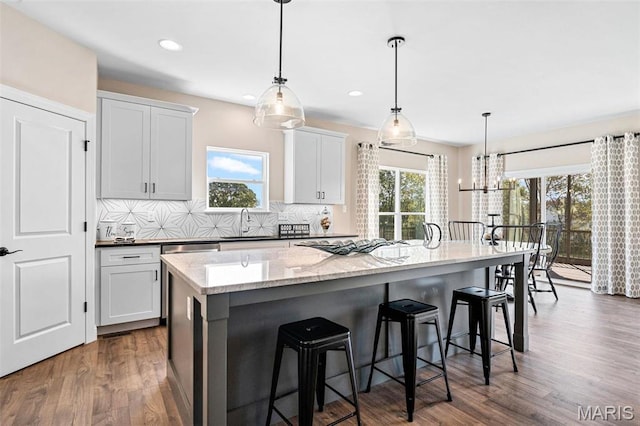 4 Challenger Ct, Ofallon, MO 63366 - kitchen featuring a kitchen island, tasteful backsplash, a sink, dark wood finished floors, and a breakfast bar area