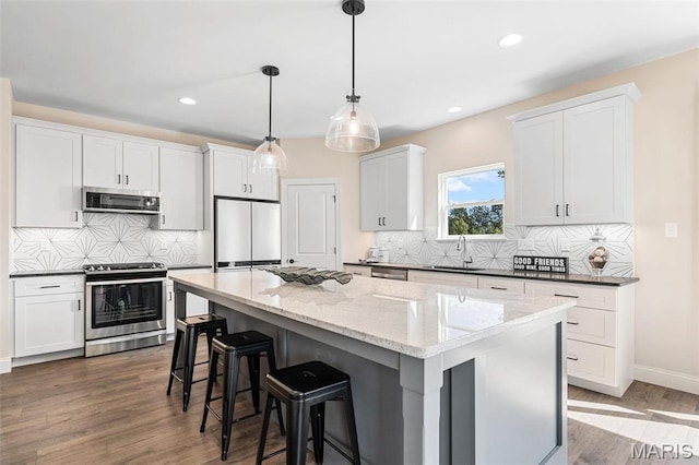 4 Challenger Ct, Ofallon, MO 63366 - kitchen featuring appliances with stainless steel finishes, a sink, a breakfast bar area, a center island, and tasteful backsplash