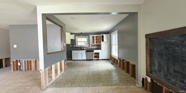 kitchen featuring dishwasher, white cabinets, a sink, and tasteful backsplash