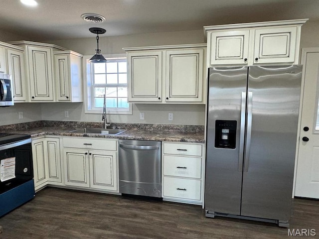 902 C St, Malden, MO 63863 - kitchen featuring appliances with stainless steel finishes, a sink, dark countertops, hanging light fixtures, and dark wood-style floors