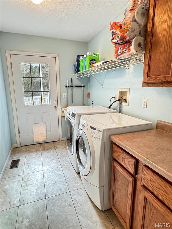 21 Forest Ln, Union, MO 63084 - laundry room featuring cabinet space, washing machine and dryer, a textured ceiling, and baseboards