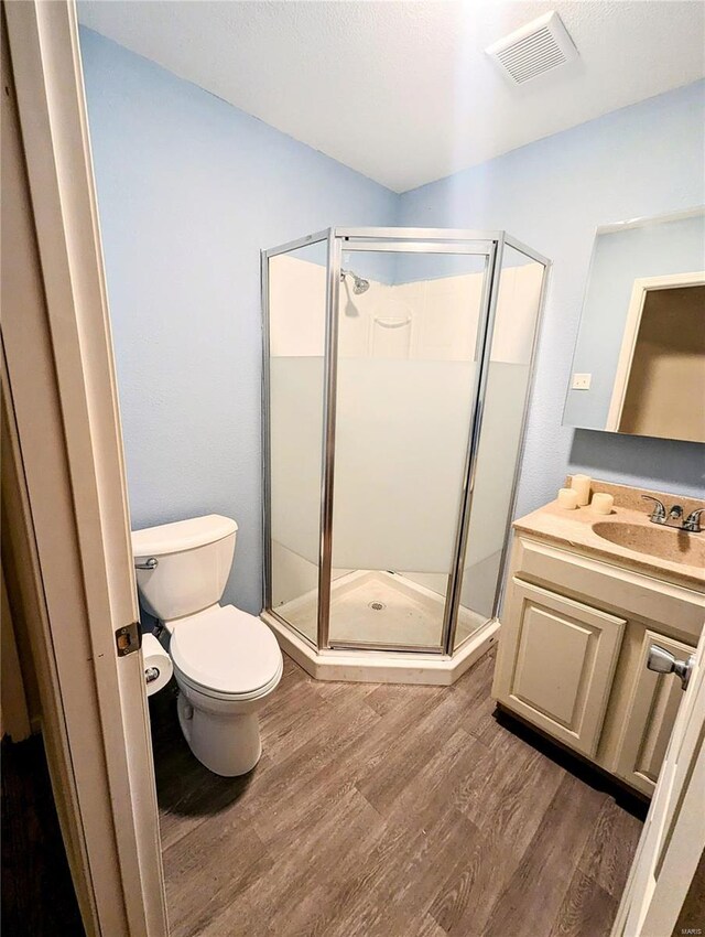 1035 Park Ave, Poplar Bluff, MO 63901 - bathroom with wood finished floors, a stall shower, toilet, and vanity