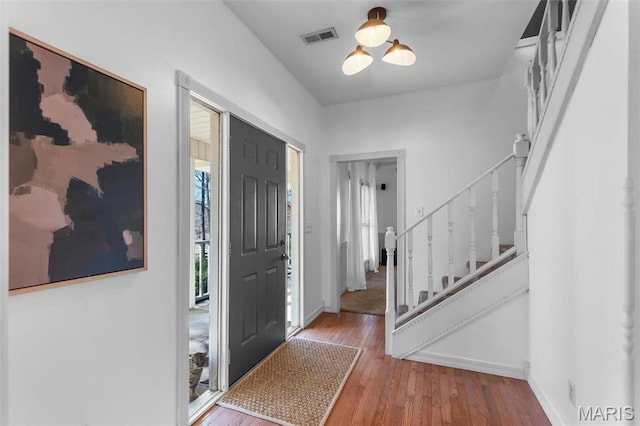 foyer entrance featuring stairway, wood finished floors, and baseboards