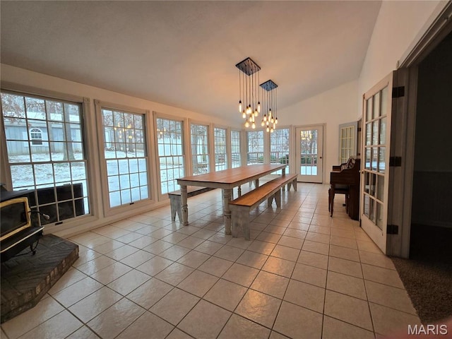 dining space featuring light tile patterned floors, a chandelier, and lofted ceiling