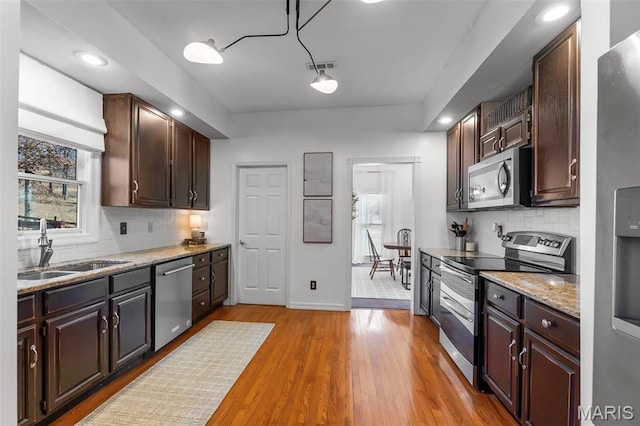 kitchen with stainless steel appliances, a sink, plenty of natural light, baseboards, and recessed lighting