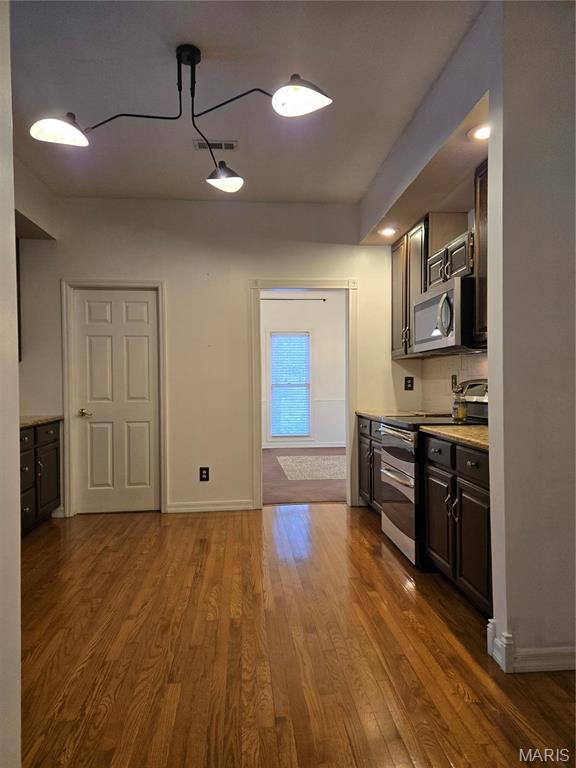 kitchen with stainless steel appliances, dark wood-style flooring, light countertops, and baseboards