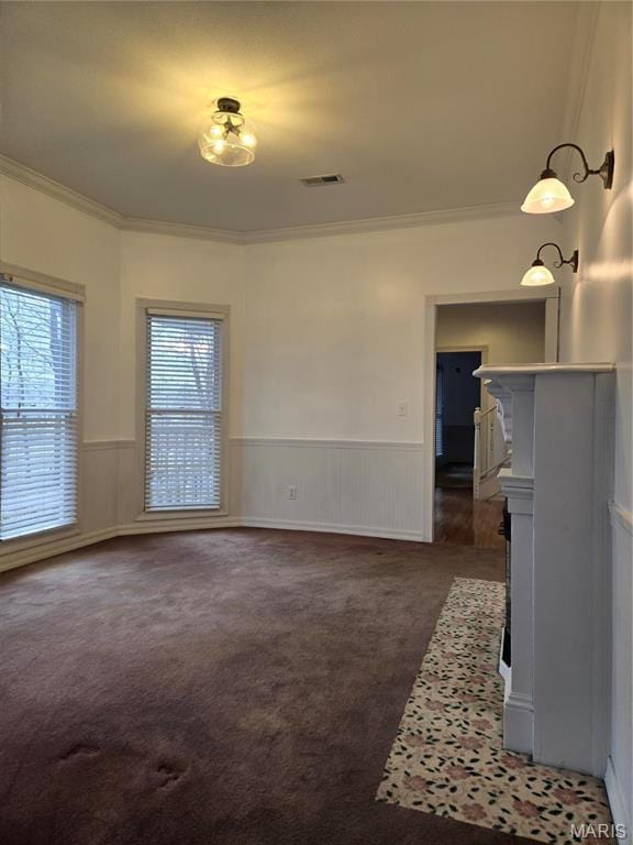 unfurnished dining area featuring ornamental molding, dark colored carpet, and wainscoting