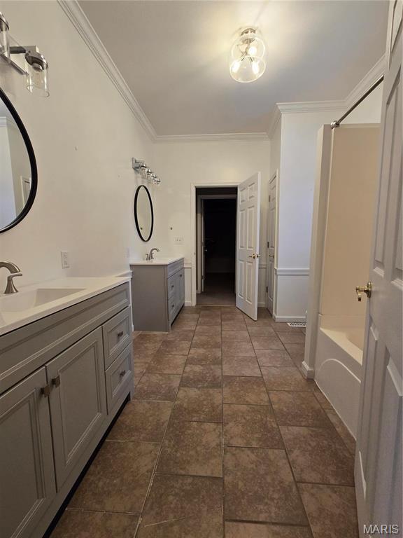 bathroom featuring ornamental molding, two vanities, and  shower combination