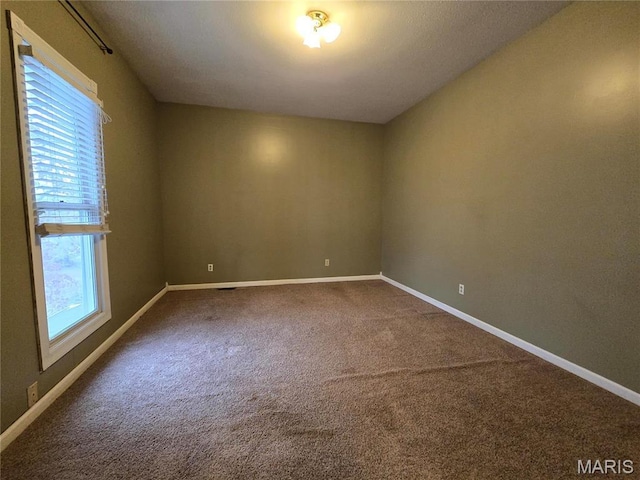 unfurnished room featuring dark colored carpet and baseboards