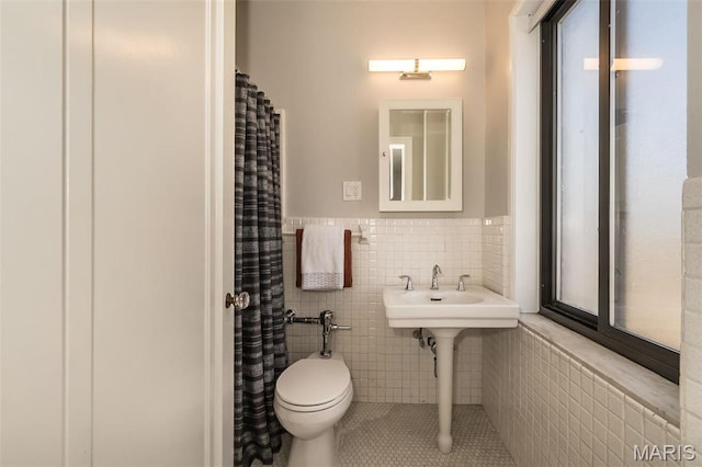 410 N Newstead Ave Unit 6W, Saint Louis, MO 63108 - full bathroom featuring tile walls, tile patterned floors, a wainscoted wall, toilet, and a sink