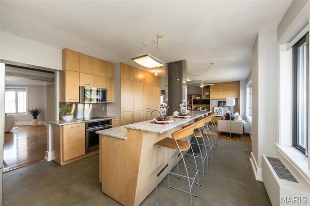 410 N Newstead Ave Unit 6W, Saint Louis, MO 63108 - kitchen with wall oven, stainless steel microwave, black electric stovetop, open floor plan, and a breakfast bar