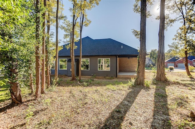 rear view of house featuring a shingled roof