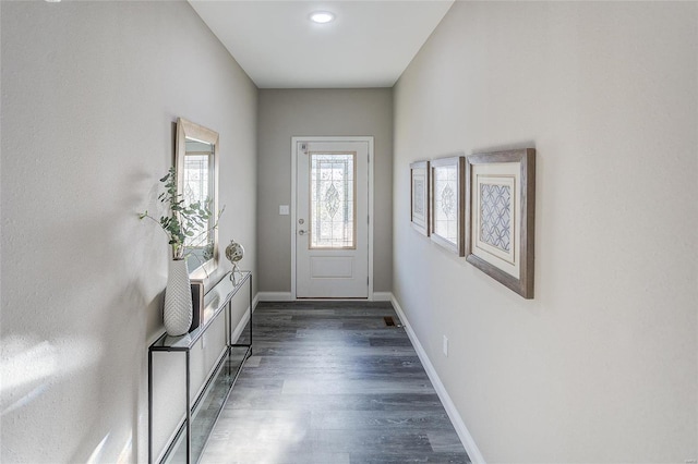 doorway with dark wood-type flooring and baseboards