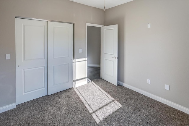 unfurnished bedroom with carpet, a closet, and baseboards