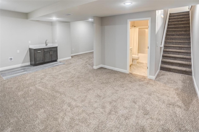 finished below grade area with light carpet, stairs, and baseboards