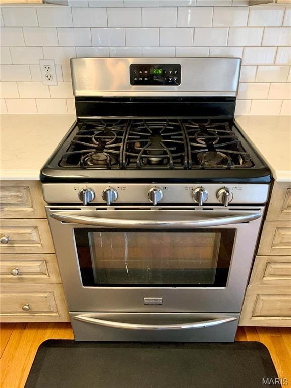 24613 Shady Oak Pl, Perry, MO 63462 - kitchen view of stainless steel gas stove, light countertops, tasteful backsplash, and light wood-style flooring