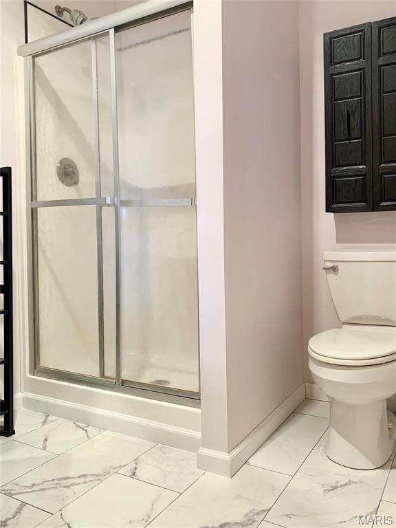 24613 Shady Oak Pl, Perry, MO 63462 - bathroom featuring marble look tiles, baseboards, and a shower stall