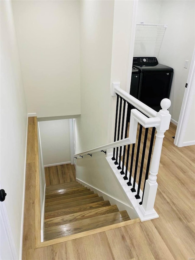stairway with wood finished floors, washing machine and dryer, and baseboards
