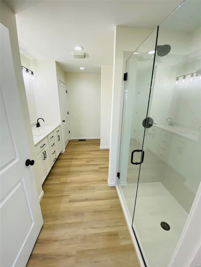 full bath featuring a shower stall, vanity, wood finished floors, recessed lighting, and baseboards